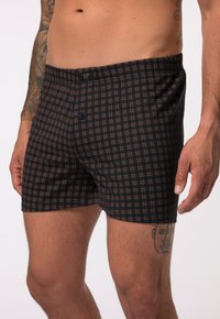 Bóxer con un patrón de cuadros en tonos azul marino y marrón, cinturilla elástica y apertura con botón. Fabricado en tejido suave y transpirable.