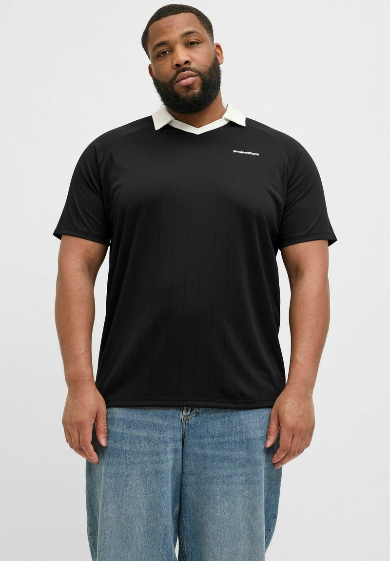 Svart kortärmad polo skjorta med vit krage, med vertikala ränder och en logotyp på bröstet. Matchad med ljusblå denim jeans.