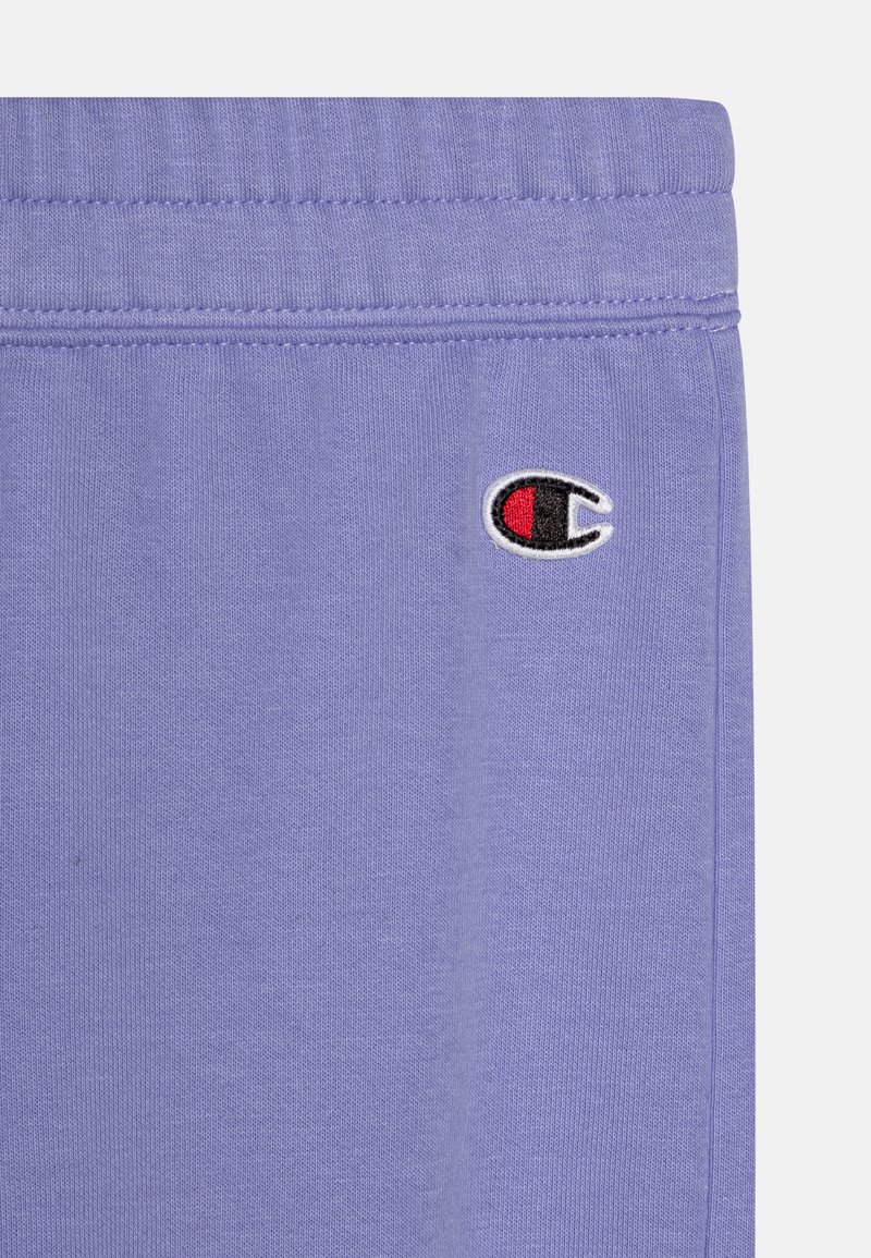 Pantaloni sportivi in cotone viola con vita elastica, cuciture laterali e un piccolo logo Champion ricamato in rosso e nero.