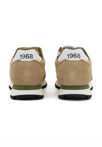 Sneaker da uomo in suede beige con accenti verdi, dotate di una linguetta sul tallone bianca stampata con "1968" e una suola bianca ammortizzata.