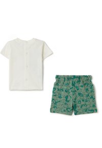 Korte mouwen witte katoenen t-shirt met drukknopen aan de achterkant, gecombineerd met groene shorts met een bloemenpatroon en een elastische tailleband.