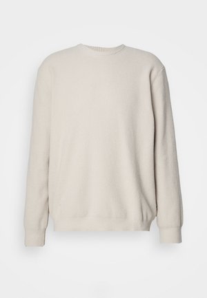 Beige langærmet sweater med ribbet tekstur, rund hals og tætsiddende manchetter. Enkel, uden udsmykning design med en løs pasform.