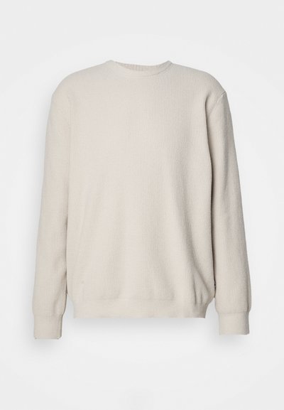 Pull à manches longues beige avec texture côtelée, col rond et poignets ajustés. Design simple et sans embellissement avec une coupe relaxée.