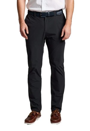 Pantalons noirs pour hommes en tissu lisse et léger, avec une coupe slim et des poches avant discrètes, associés à des chaussures bateau marron.