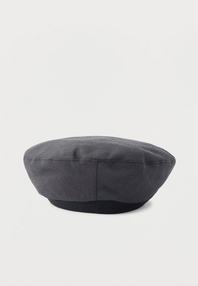 Béret en velours côtelé gris foncé avec bande élastique noire, forme plate et ronde, présenté sur un fond uni clair.