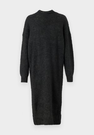 Lang svart genserkjole laget av fluffy stoff med høy hals, nedre skuldre og lange ermer. Har en rett silhuett og sideslits.