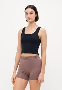 Black cropped tank top and brown UGG boxer shorts. The tank has a scooped neckline, while the shorts feature a logoed waistband. Smooth fabric texture.