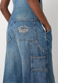 Denimbyxor i ljusblått med strukturerad yta, med stora fickor och broderad "Tommy Jeans"-logotyp i krämfärg på bakfickan.