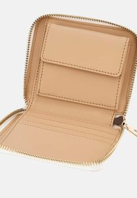 Portafoglio zip-around in pelle beige chiaro con hardware dorato. Presenta una fessura per carte, un compartimento più grande e una texture liscia.