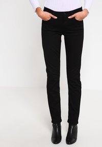 Mustat kapeat farkut joustavasta puuvillasekoitekankaasta, joissa on viisi taskua, istuva malli ja hillityt ompelu-yksityiskohdat.