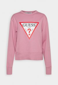 Sweat-shirt rose à col rond, manches longues, poignets côtelés, avec un logo triangulaire rouge et noir affichant « GUESS » et un point d'interrogation.
