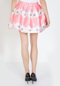 Falda floral con cintura elástica y fruncida; presenta patrones de acuarela en rosa claro y blanco con acentos de flores negras. Textura de satén.