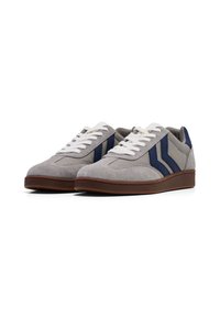 Grijze suède sneakers met witte veters, blauwe streepaccenten en een bruine rubberen zool. Beschikt over een ronde teen en een gevoerde kraag voor comfort.