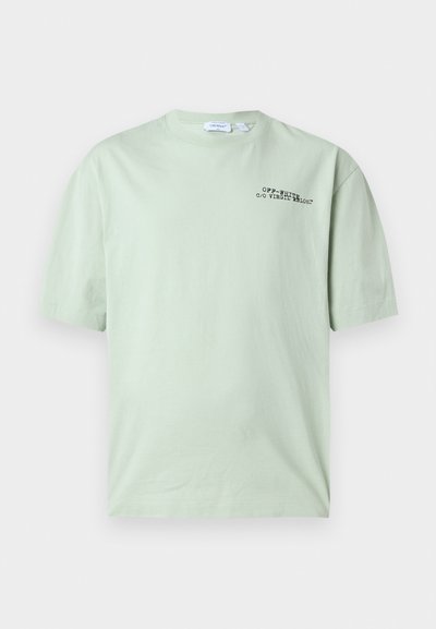T-shirt vert clair à manches courtes avec texte noir « OFF-WHITE c/o VIRGIL ABLOH™ » sur le côté gauche de la poitrine.