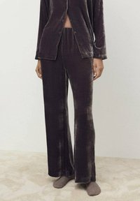 Samtkuscheljogginganzug in Dunkelbraun, bestehend aus einem Hemd mit Knopfleiste und passenden weiten Hosen mit elastischem Bund und weicher Textur.