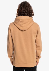 Felpa beige con cappuccio regolabile, maniche lunghe e vestibilità comoda. Tessuto liscio con polsini e orlo a coste.