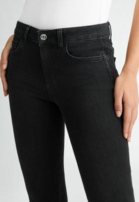 Jeans in denim nero con una vestibilità slim, caratterizzati da un design a cinque tasche, chiusura con bottone argentato e dettagli di cucitura discreti sulle tasche.