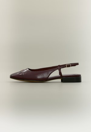 Zapato slingback de cuero marrón oscuro con punta puntiaguda, tacón bajo y apilado, y correa ajustable con hebilla sobre un fondo neutro.