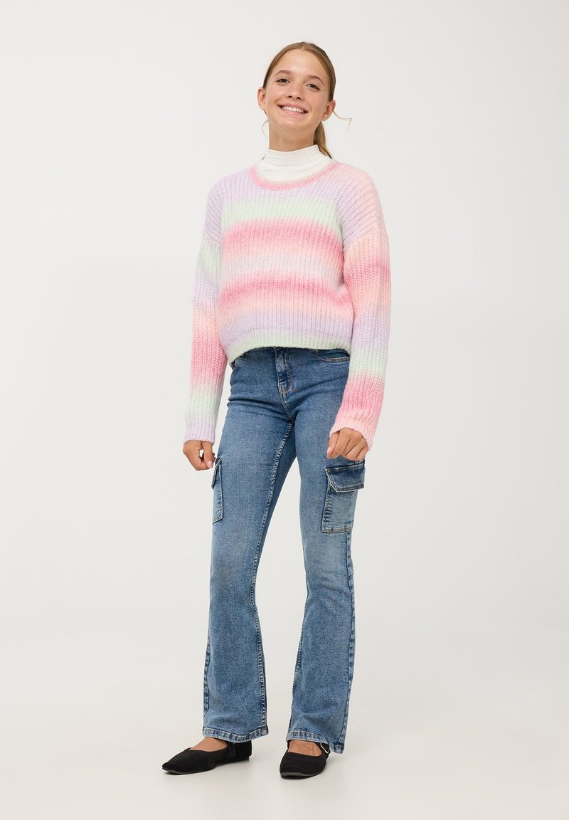 Sweter dzianinowy w pastelowych odcieniach różu i zieleni; wysoka szyja, lu�źny krój. Para jasnoniebieskich, rozszerzających się spodni cargo z kieszeniami.