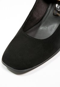 Czarne zamszowe szpilki o kwadratowym nosku i gładkiej podszewce. Posiadają niski, solidny czarny obcas oraz subtelne detale przeszycia wzdłuż otwarcia.