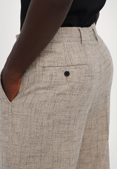 Beige gestreepte broek van textuurstof, met een achterzak met een enkele zwarte knop en een rechte pasvorm.