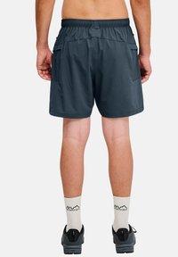 Blauwe sportshorts met een elastische taille, twee zijzakken en een lichte, gladde textuur. Gemaakt met witte sokken en zwarte schoenen.