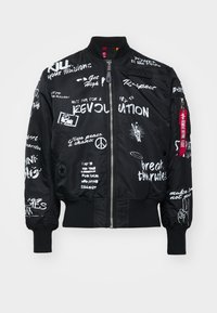 Black bomber jacket with white graphics and text. Features a zip front, ribbed cuffs, and a patch on the chest. Text includes slogans and symbols.