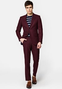 Burgundowy garnitur o dopasowanym kroju, zestawiony z granatową koszulą w paski. Buty w kolorze brązowym z podwójnym zapięciem typu monk strap. Całość ma gładką teksturę.