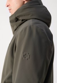 Olijfgroene jas met een hoge kraag en capuchon. Heeft een gladde, matte textuur en een subtiele logo-embossing op de linkermouw.