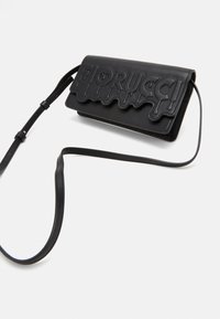 Schwarze Leder-Crossbody-Tasche mit einer strukturierten Klappe, die tropfende Schriftzüge zeigt. Verstellbarer Riemen, kompakte rechteckige Form, glatte Oberfläche.