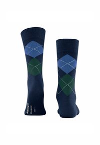 Un par de calcetines azul marino con patrones de diamantes en argyle azul y verde y detalles de costura blanca.