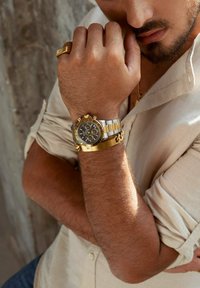 Chronograph-Uhr mit schwarzem Zifferblatt, goldenen Akzenten und silbernem Armband. Merkmale sind ein markantes Zifferblatt, Nebenzifferblätter und eine polierte Oberfläche der Metallbänder.