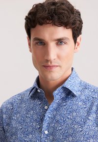 Camicia blu a motivo floreale, con colletto classico e chiusura a bottoni, realizzata in tessuto leggero.