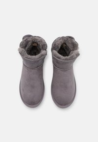 Bottines en suède gris avec un intérieur en fourrure grise douce, descoutures sur la cheville et une conception à bout rond.