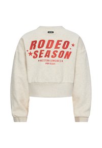 Przycięty, jasnobeżowy sweter z odważnym czerwonym napisem: "SEZON RODEO" z gwiazdkami oraz "WESTERN COWGIRLS 1989 TEXAS" poniżej. Miękka tekstura.