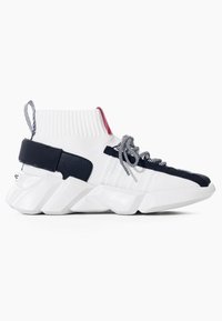 Sneaker bianco alto con accenti neri e rossi, lacci a righe, polsino alla caviglia a coste, suola geometrica testurizzata e linguetta sul tallone.