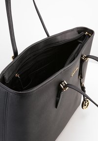 Sort syntetisk tote taske med en struktureret overflade, gyldent hardware, dobbelte håndtag og flere indvendige rum, herunder lynlåslommer.