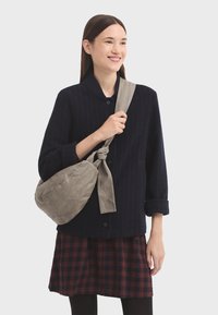 Svetrová bunda s námořnickými pruhy, límcem a knoflíky, v kombinaci s červenou a černou kostkovanou sukní a šedou látkovou crossbody taškou.