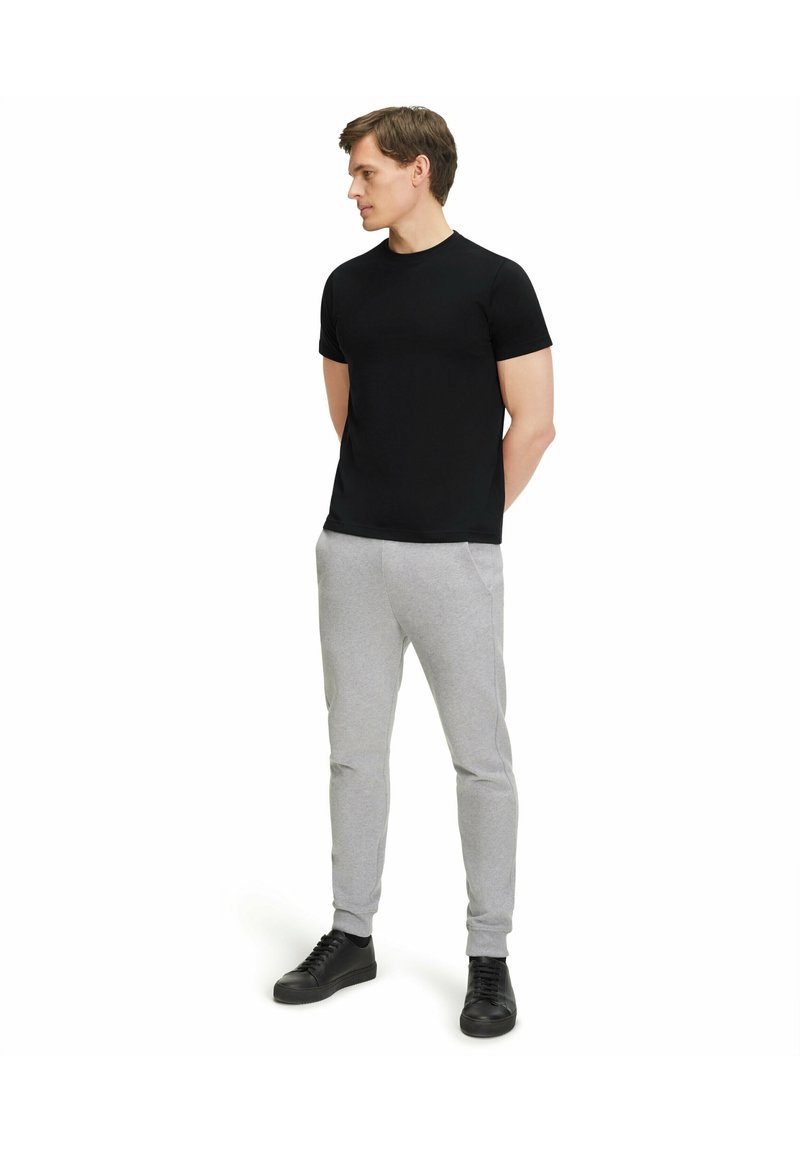 Black short-sleeve t-shirt paired with light gray joggers. The joggers have elastic cuffs and side pockets. Black sneakers complete the outfit.