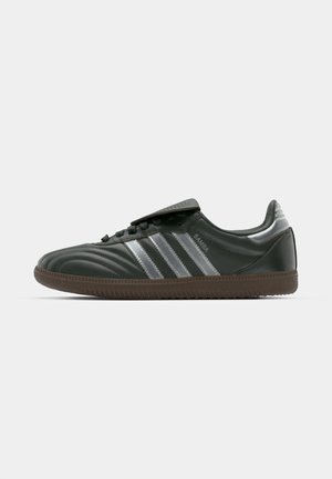 Sneakers in pelle nera con strisce argentate, superficie testurizzata, punta tonda e suola in gomma marrone. Presentano chiusura con lacci e linguetta imbottita.