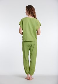 Completo verde a due pezzi in tessuto leggero, con top a maniche corte e pantaloni con polsini elasticizzati e finitura texturizzata.