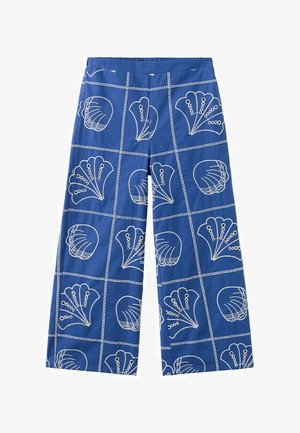 Pantalon large bleu avec des lignes blanches en quadrillage et des motifs abstraits de fleurs et de coquillages répartis uniformément sur le tissu.