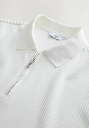 White ribbed polo shirt featuring a half-zip front, a soft collar, and subtle texture. Tag inside indicates brand and fit information.