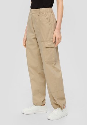 Beige cargobroek met elastische tailleband, voorzien van zijzakken en een patchzak op het been. De stof is glad en de pasvorm is ontspannen.