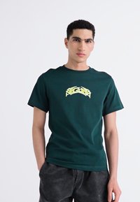 Dark green cotton t-shirt featuring a yellow graphic design on the front, round neckline, short sleeves, and a regular fit.