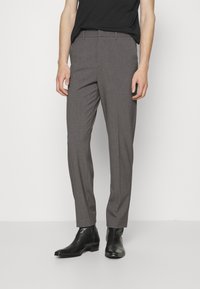 Šedé kalhoty na míru se slim fit, vyrobené z texturované látky, s předními kapsami a hladkým povrchem, doplněné černými společenskými botami.