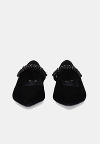 Bailarinas de ante negro con punta afilada, que presentan una tira de cuentas negras a lo largo del empeine. Textura suave con acentos decorativos.