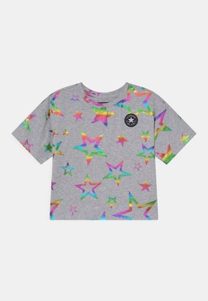 T-shirt gris à manches courtes avec des motifs d'étoiles métalliques multicolores et un petit logo noir Converse All Star sur la partie supérieure gauche de la poitrine.