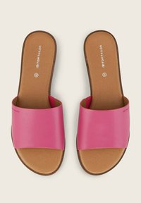 Roze schuif-sandalen hebben brede, gladde banden en een platte, bruine binnenzool. Het ontwerp is eenvoudig, met een zachte textuur en minimale details.