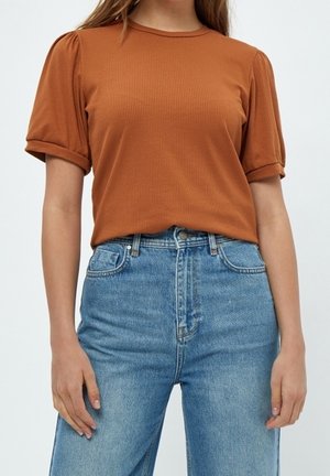 Top marron à manches courtes côtelé avec des poignets retournés, associé à un jean en denim bleu clair taille haute. Les deux articles ont une coupe décontractée.